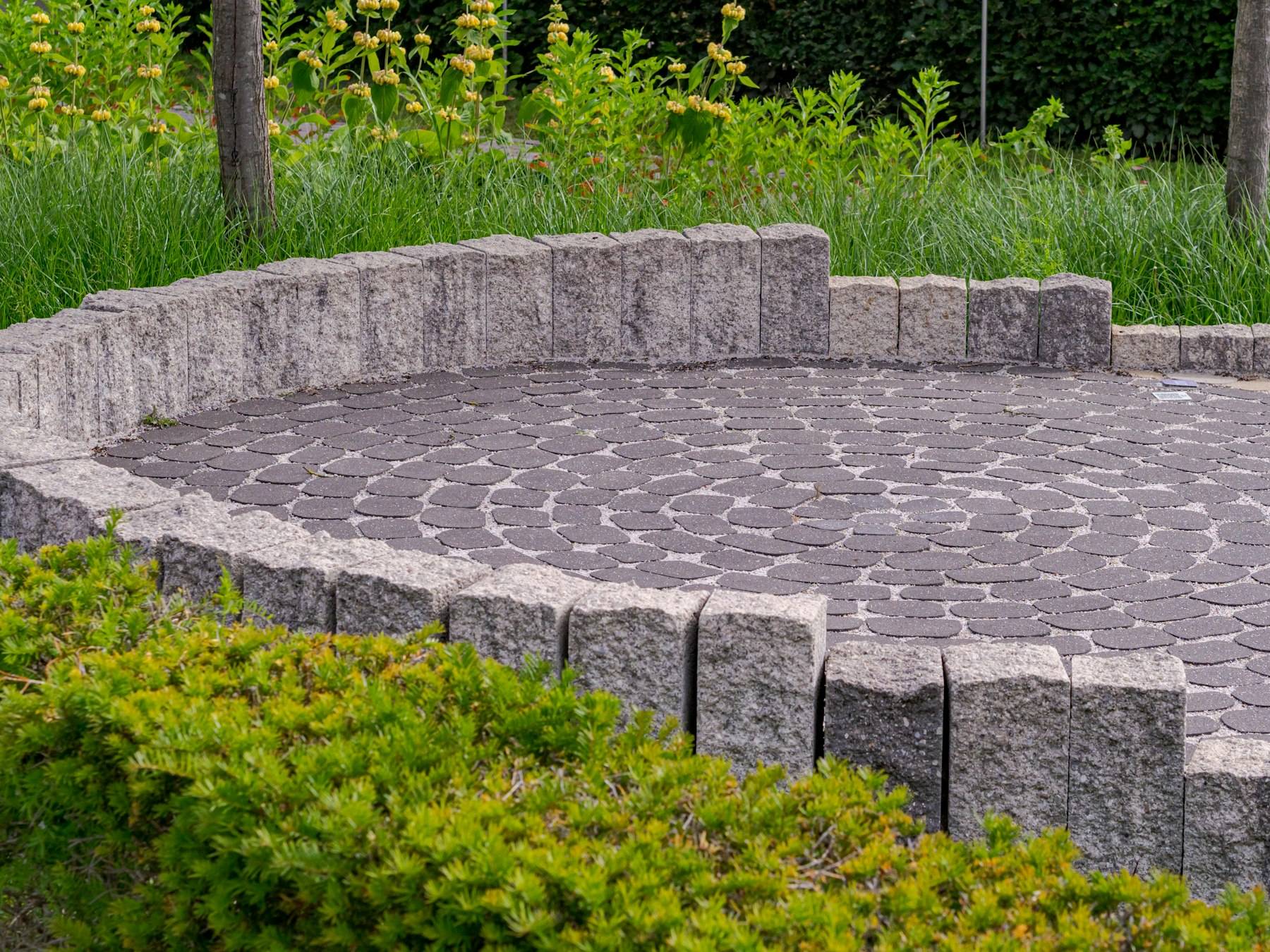 Round paver patio framed by a low stone wall